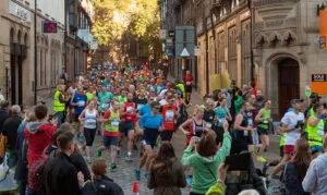Narrow cobbled streets, crowded with runners and spectators, at the start of the Chester Marathon