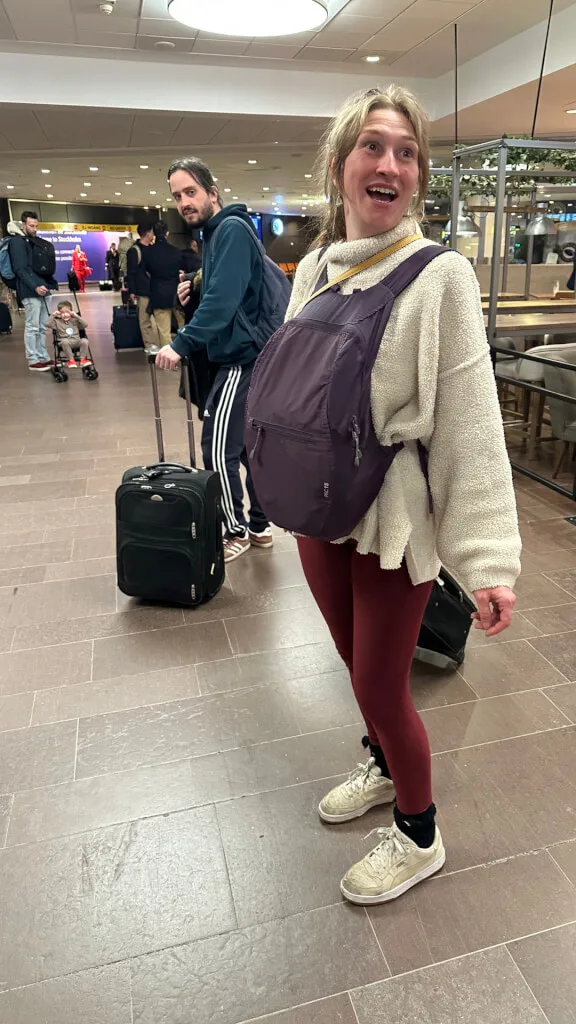 Annelie in Manchester Airport, with the purple holdall strapped round her neck, carrying the ashes on her stomach as if she was heavily pregnant.