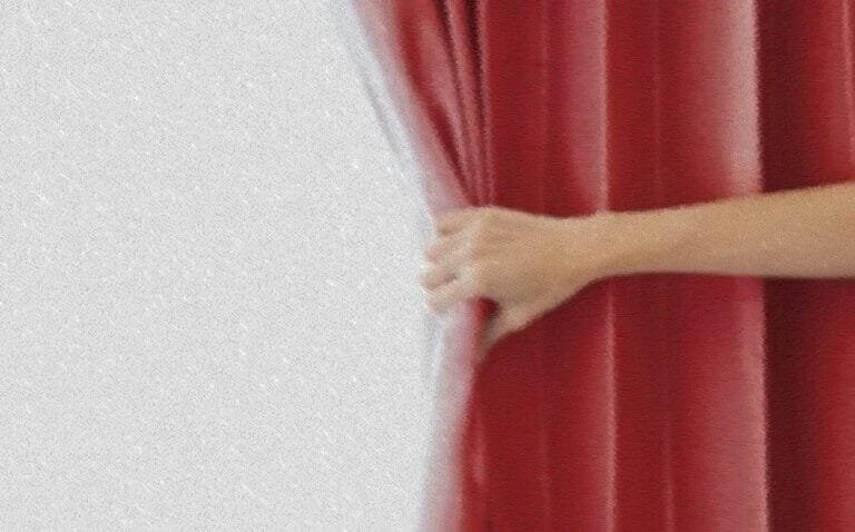 A hand is opening a red curtain to the world