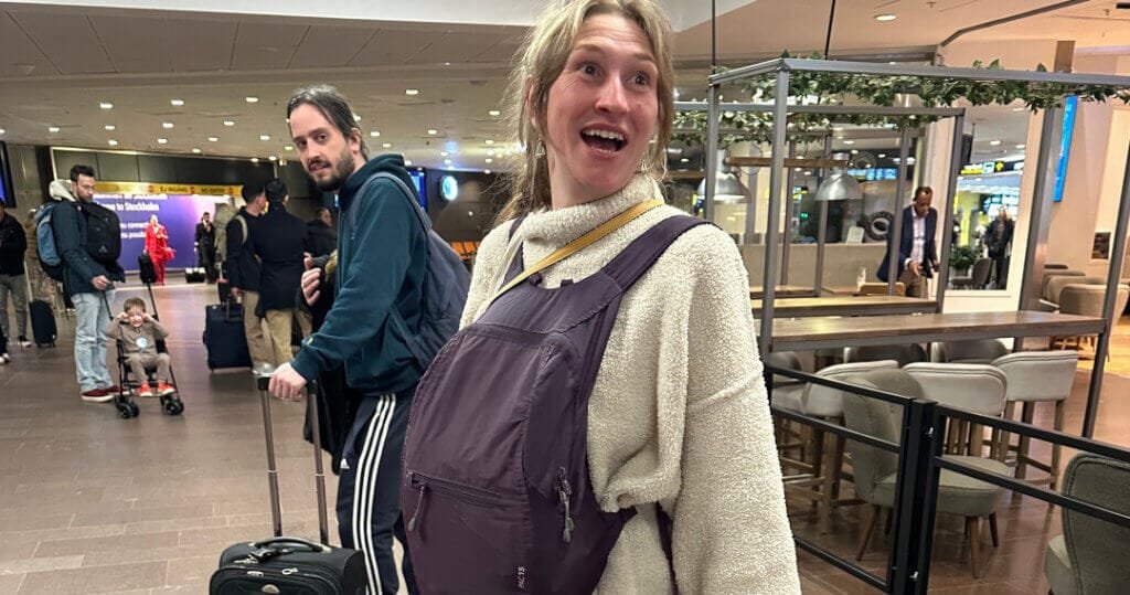 Annelie in Manchester Airport, with the purple holdall strapped round her neck, carrying the ashes on her stomach as if she was heavily pregnant.